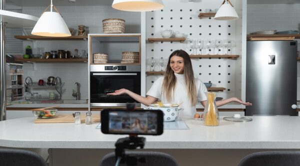 Young vlogger woman vlogging about cooking at her apartment dome