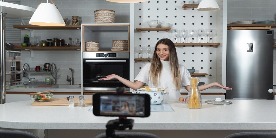 Young vlogger woman vlogging about cooking at her apartment dome